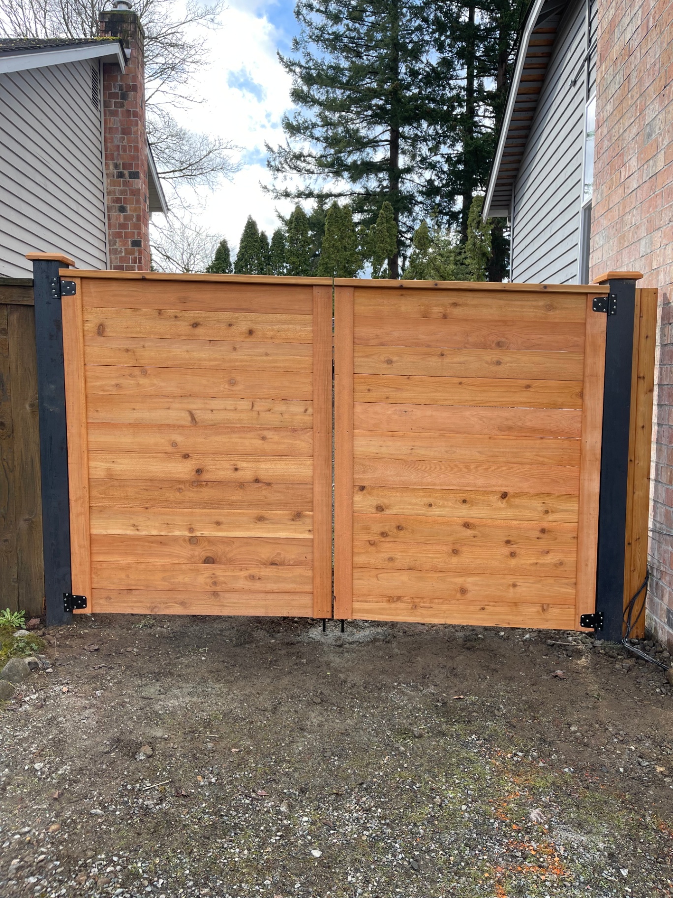 Horizontal cedar fence gate with black metal posts