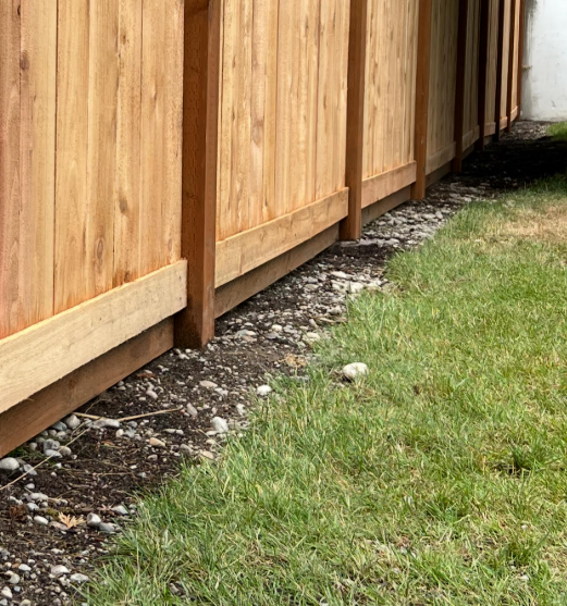 Excavated soil roughly raked along fence line allowing grass regrowth